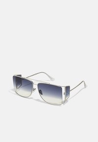 Occhiali da sole con montatura in metallo argentato e lenti grigie sfumate. Forma angolare con ritagli distintivi nella parte superiore e branding sottile.