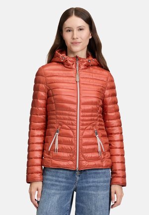 Veste rembourrée zippée orange avec une capuche, présentant une texture côtelée, des poches latérales et des détails de fermeture éclair contrastants.