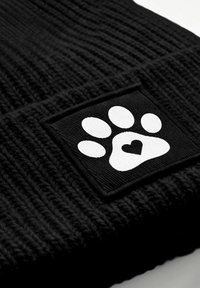 Black knitted fabric with a white paw print patch featuring a heart shape inside the paw's pad.