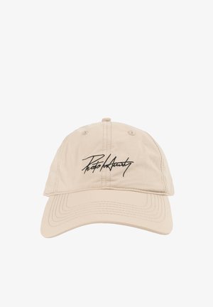 Beżowa czapka baseballowa z zakrzywionym daszkiem i czarnym tekstem pisanym kursywą wyhaftowanym na środku przodu.