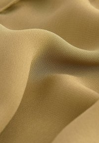 Țesătură de aur deschis, cu o textură netedă, prezentând pliuri subtile și un ușor luciu, având o culoare uniformă fără modele.