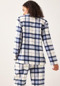 Blå och vit rutigt flanellset som innehåller en knapp-up topp med långa ärmar och matchande byxor, med en mjuk textur och fyrkantig passform.