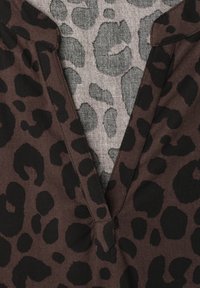 Close-up of brown fabric with black leopard print on garment collar over gray fabric with lighter leopard print pattern.