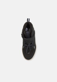 Basket montante noire en tissu texturé, avec des lacets et une sangle en velcro. Comprend un col rembourré et une semelle en caoutchouc avec un bord contrasté.