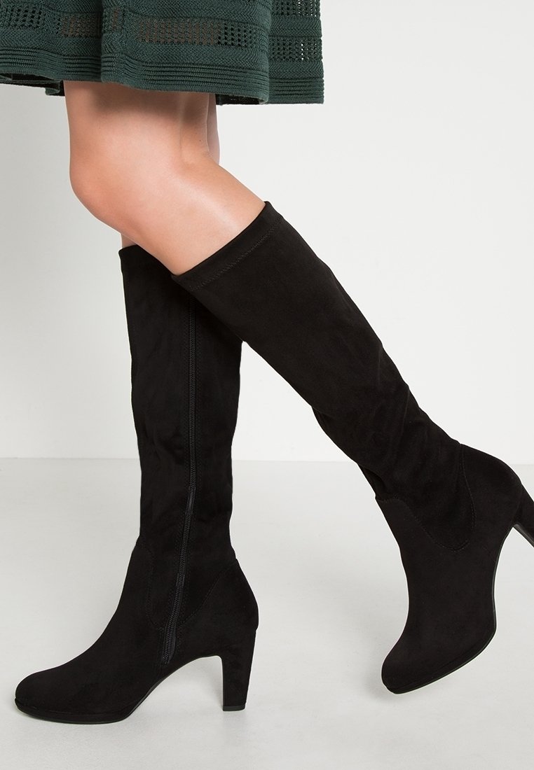 Stivali alti neri in suede con tacco alto, dotati di una cerniera laterale e una texture liscia. Il design è elegante e aderente.