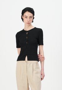 Zwarte ribgebreide cardigan met korte mouwen, een ronde hals en een knoopsluiting aan de voorkant. Heeft een iets cropped pasvorm en een open frontgedeelte.