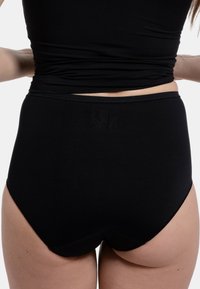 Mutandine in cotone nere a vita alta con una superficie liscia. Presentano cuciture minime e una cintura morbida. Elastiche per garantire comfort.