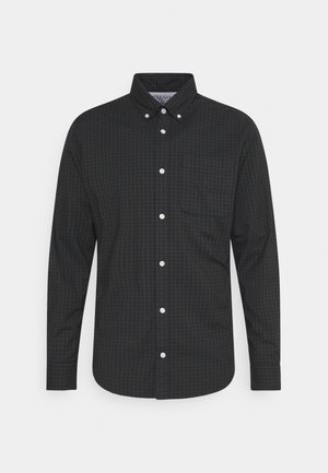Ciemna koszula w kratę z długim rękawem, zapinana na guziki, z kołnierzykiem na guziki i pojedynczą kieszenią na piersi.