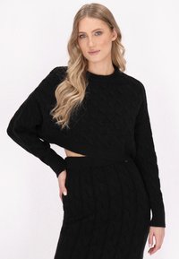 Schwarzer, kabelgestrickter, kurz geschnittener Pullover mit langen Ärmeln, kombiniert mit einem passenden schwarzen, kabelgestrickten Rock, der ein strukturiertes Muster und einen elastischen Taillenbund aufweist.