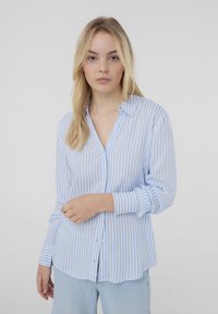 Camicia a righe blu chiaro e bianca con colletto, maniche lunghe e vestibilità rilassata, realizzata in un tessuto liscio e leggero.