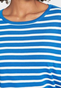 Modrý a bílý pruhovaný pletený top s kulatým výstřihem. Má vodorovné pruhy a hladkou strukturu, vhodný pro běžné nošení.
