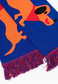 Dzianinowy szalik z niebieskim tłem i pomarańczowym wzorem psa. Frędzle w kolorach czerwonym i niebieskim. Wykonany z miękkiego, teksturowanego materiału.