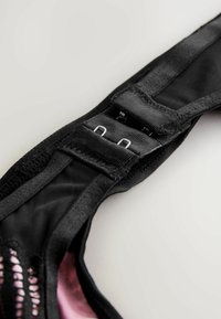 Fekete melltartópánt, állítható hardverrel, puha anyagból és belső hálós részletekkel. A pánt több rögzítési lehetőséget kínál.