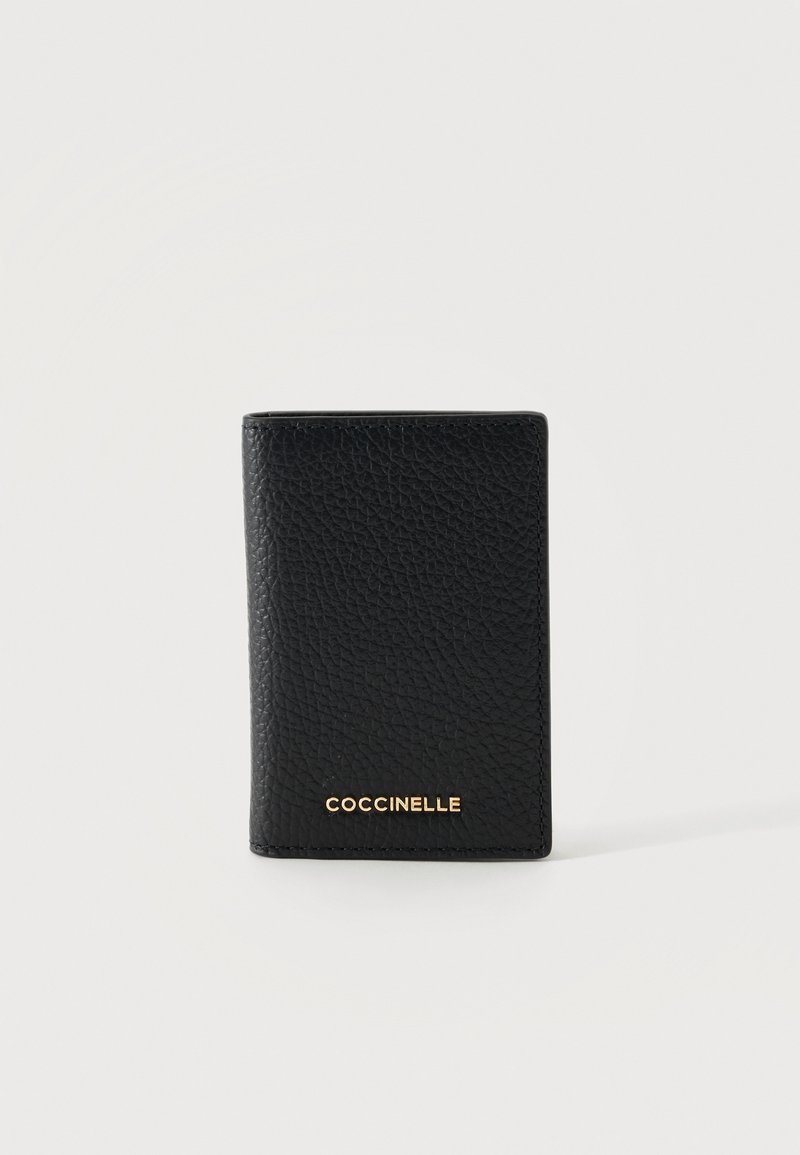 Portefeuille en cuir texturé noir debout, avec le logo doré "COCCINELLE" centré près du bas sur un fond blanc uni.