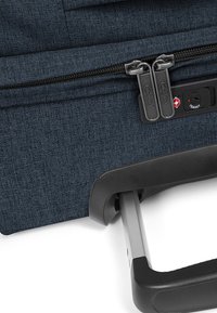 Navy fabric suitcase featuring dual zipper pulls, a TSA-approved lock, a sturdy retractable handle, and a textured surface.