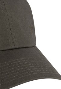 Khaki basebalová čiapka s zakriveným okrajom, vyrobená z odolnej tkaniny. Obsahuje jemný hnedý vyšívaný logotyp a textúrované šitie na okraji.