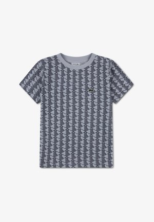 Kortermet T-skjorte i lys grå med et geometrisk svart mønster. Har rund hals og en liten Lacoste-logo på brystet.