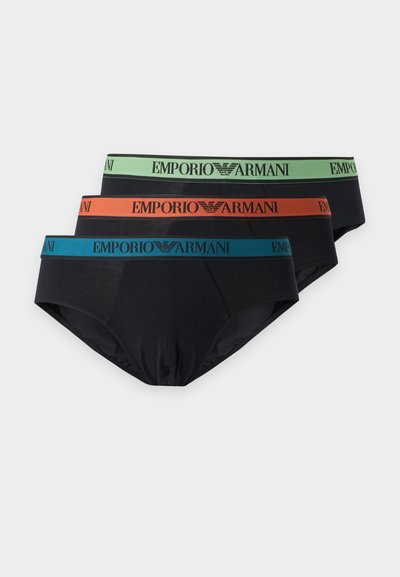 Trois slips noirs Emporio Armani empilés, chacun avec une ceinture de couleur différente en vert, orange et bleu, portant le nom et le logo de la marque.