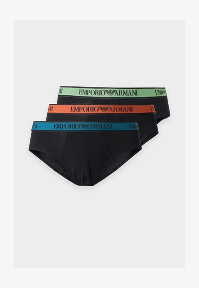 Trois slips noirs Emporio Armani empilés, chacun avec une ceinture de couleur différente en vert, orange et bleu, portant le nom et le logo de la marque.