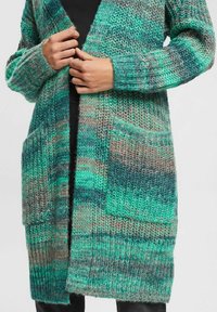 Sweter kardigan w odcieniach niebieskiego i szarości, o grubym splocie, z otwartym przodem i dwoma przednimi kieszeniami. Długie rękawy z prążkowanymi mankietami.