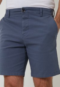 Marineblaue lässige Shorts aus weichem Stoff, mit Seitentaschen, einem Frontknopfverschluss und geradem Schnitt über dem Knie.