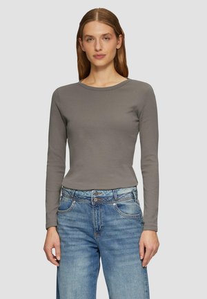 Langsleeve, aansluitend top van zacht grijs stof met een ronde halslijn, gecombineerd met lichtblauwe jeans met knoopsluiting en versleten details.