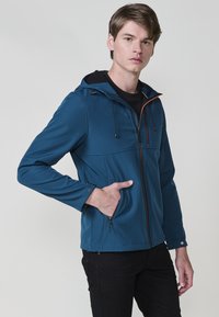 Giacca soft-shell blu da uomo con cappuccio, dotata di zip frontale, due tasche laterali e dettagli con zip arancione a contrasto.