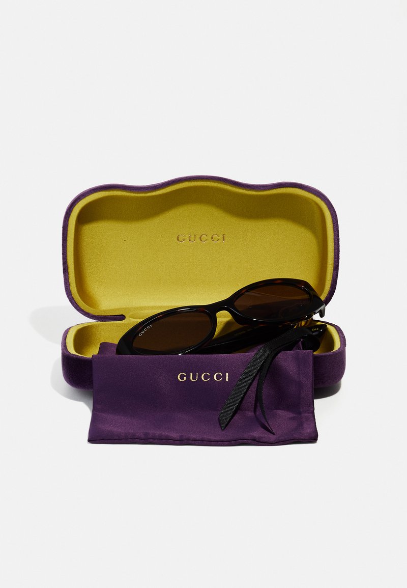 Gucci sunglasses in a purple case with yellow lining, featuring a soft fabric pouch and black frames with dark lenses.