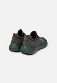 Scarpe da ginnastica verde scuro con tomaia in mesh testurizzato, colletto elastico e suola in gomma robusta. Presentano un marchio discreto e una forma aerodinamica.