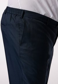 Pantalones azul marino con una tela texturizada, cinturilla elástica y bolsillos laterales. El diseño presenta un corte slim y un acabado suave.