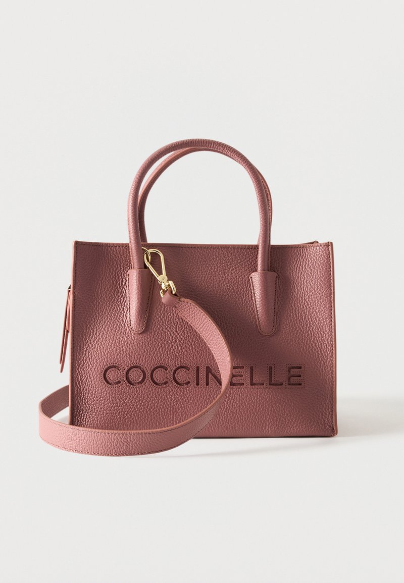 Sac à main en cuir rose texturé avec deux poignées, une bandoulière détachable et "COCCINELLE" embossé sur le devant.