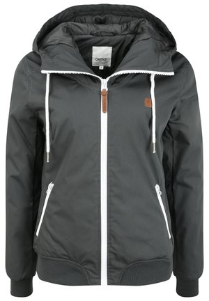 Giacca a vento grigia scura con cappuccio realizzata in tessuto liscio, caratterizzata da zip bianca, polsini elastici, due tasche frontali e un piccolo patch in pelle marrone.