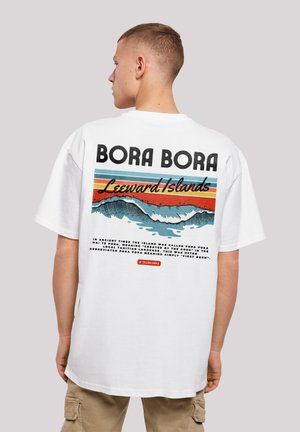 White graphic t-shirt featuring "BORA BORA" text, waves, and colorful stripes on the back. Relaxed fit, cotton material, casual design.