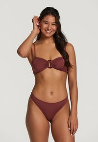 Bordo bikini komplekts ar ručotu dizainu un centrālo sprādzi. Augšdaļai ir plānas siksnas, bet apakšdaļa ir augstajā griezumā.