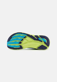 Semelle de chaussure avec une base verte, des accents bleus et noirs. Présente des motifs de grip texturés et des cannelures pour une meilleure adhérence.