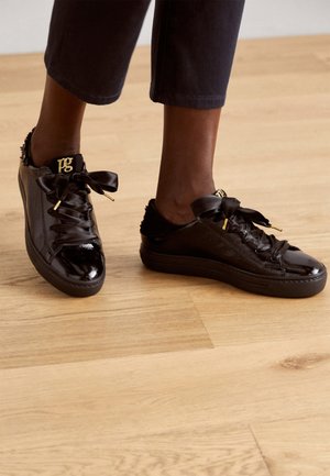 Schwarze Lackledersneaker mit Ripsband-Schnürsenkeln, goldenen Hardware-Akzenten und einem strukturierten Design. Verfügt über ein flaches Profil und eine Gummisohle.