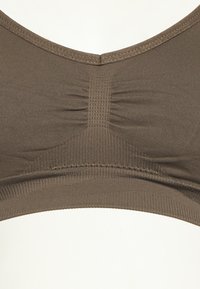 Bralette castanho sem costuras com um frente texturizada, ampla banda inferior e tecido macio. Apresenta um decote redondo e detalhes de costura subtis.