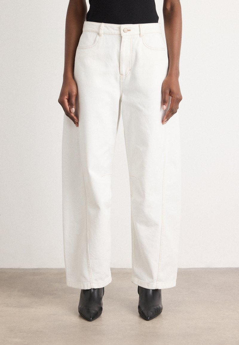 Hvite vide jeans med kontrastsøm, høy midje og fire lommer, kombinert med svarte høyhælte ankelstøvletter. Glatt denimtekstur.