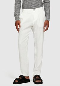 Vita linnebyxor med rak passform och svart knappstängning. Matchat med svarta sandaler med tjocka remmar och plattformssula.