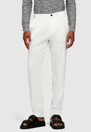 Pantaloni bianchi in lino con taglio dritto e chiusura a bottone nero. Abbinati a sandali neri con spesse cinghie e suola platform.