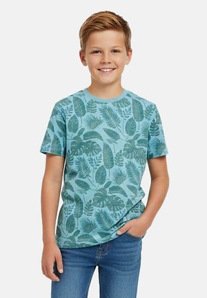 Lichtblauw T-shirt met korte mouwen en een groen bladvormig patroon. Materiaal lijkt zacht; ronde hals; gecombineerd met een blauwe spijkerbroek.