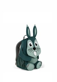 Grüner, hasenförmiger Rucksack aus weichem Material, mit auffälligen Ohren, großen Augen und einem lächelnden Mund. Mit Reißverschlussfächern an der Vorder- und Unterseite.