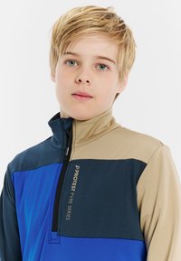 Pullover con zip al collo in pannelli blu navy, blu e beige. Tessuto liscio con vestibilità comoda. Presenta un logo sul petto e un colletto alto.