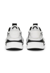 Baskets de sport blanches et noires avec une tige en maille, un talon rembourré et une semelle texturée. Présente un grand tirant à l'arrière et des bandes d'accent.