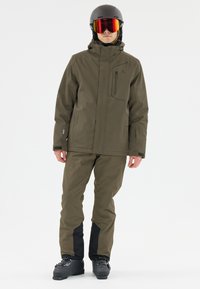 Olivgrüne wasserdichte Skijacke mit hohem Kragen, Reißverschluss-Brusttasche und passenden olivfarbenen Hosen mit schwarzen Akzenten an den Knöcheln.