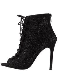Zwarte suède enkellaars met open teen, versierd met kleine glanzende accenten, met een vetersluiting aan de voorkant en een stilettohak.
