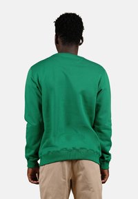 Felpa verde con scollatura e polsini a coste, caratterizzata da una texture uniforme e una vestibilità comoda. Cuciture visibili all'orlo.