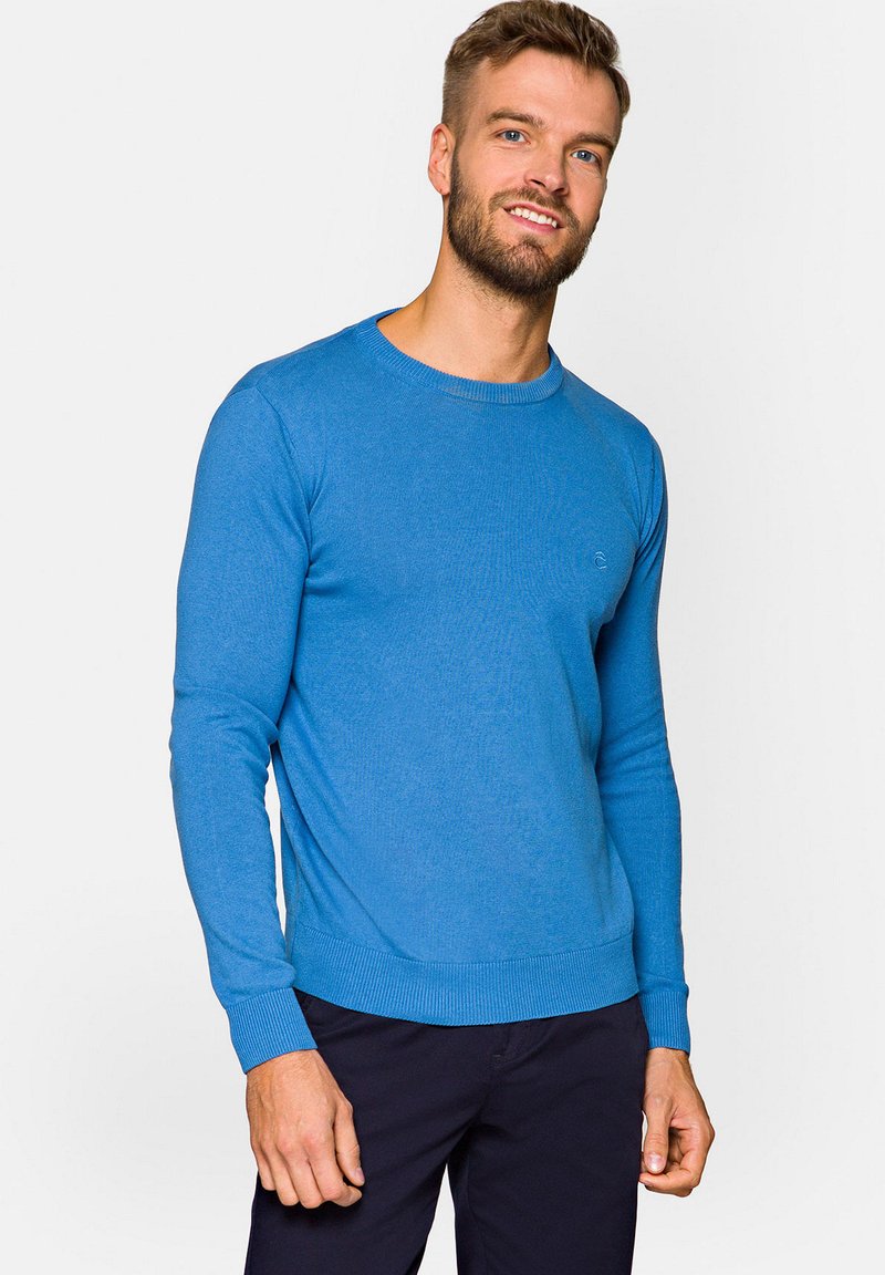 Niebieski sweter z długim rękawem, wykonany z dzianiny, z okrągłym dekoltem, prążkowanymi mankietami i dołem. Posiada małe logo na klatce piersiowej oraz gładką teksturę.