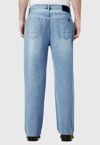 Svetlo modre kavbojke iz jeansa, pogled od zadaj, z ravnimi hlačnicami, dvema zadnjima žepoma in črnim pasom kot poudarkom.