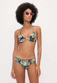 Two-piece bikini featuring a black background with colorful leaf patterns, triangle top with ties, and matching bikini bottom. Smooth fabric.